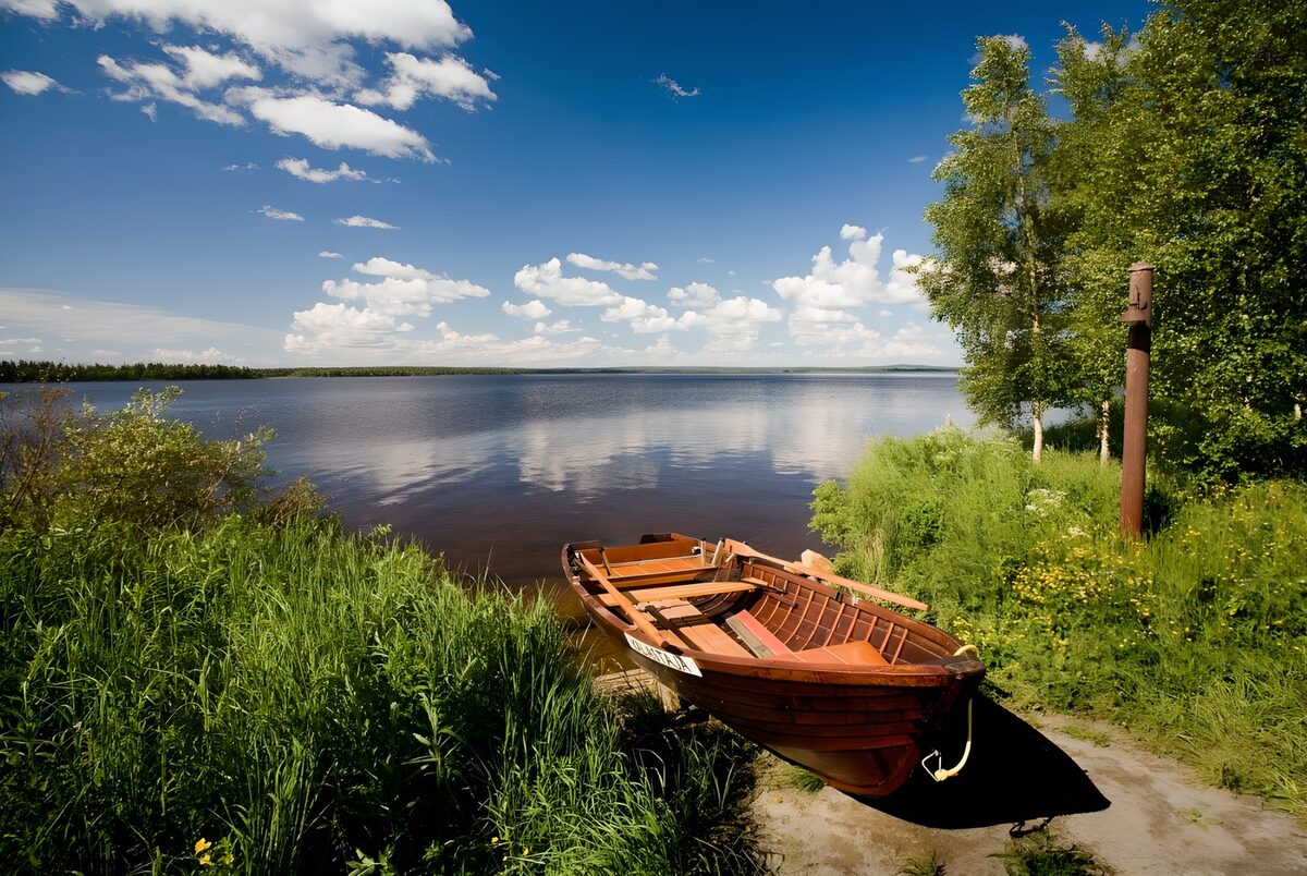 Holzruderboot am sommerlichen Seeufer