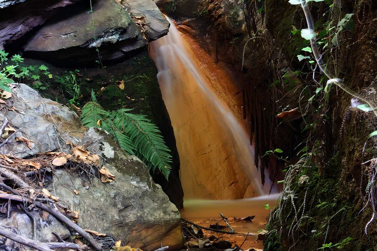 Schmaler Wasserfall zwischen dunklen Felsen