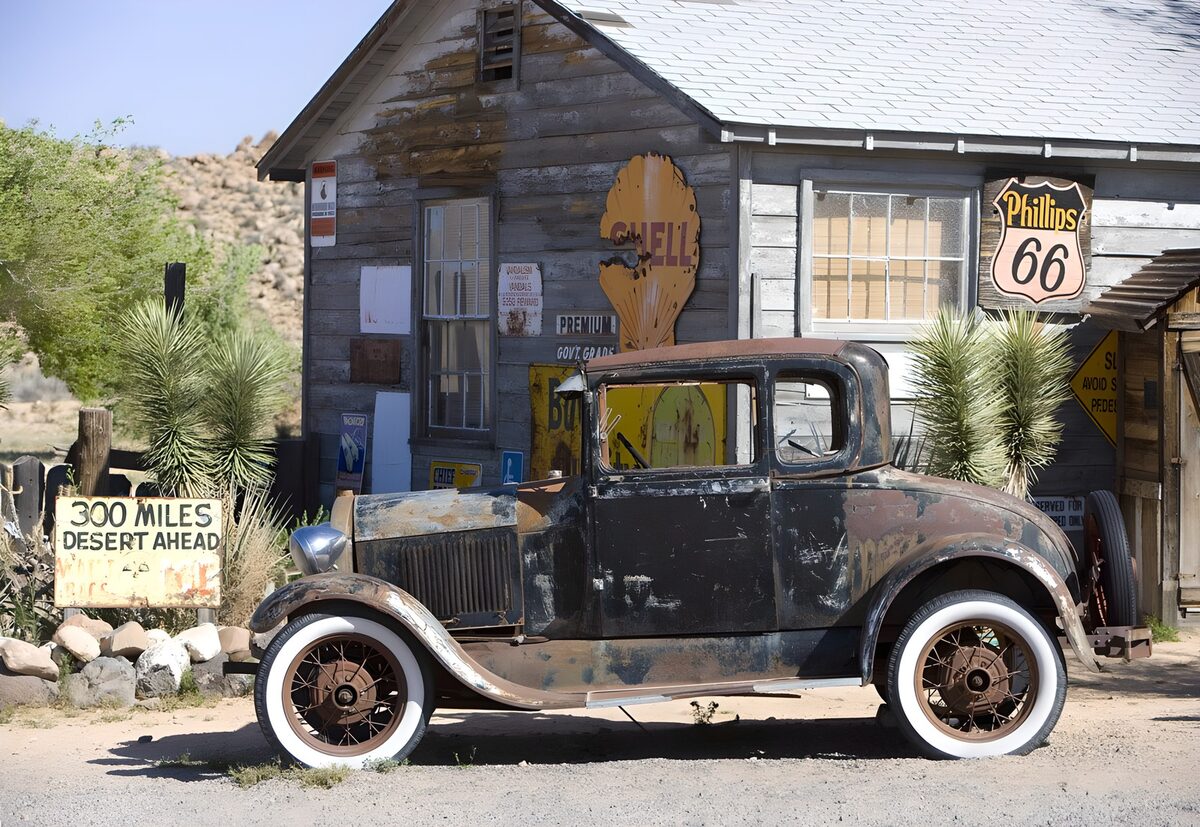Rostiger Oldtimer vor grauer Holzfassade