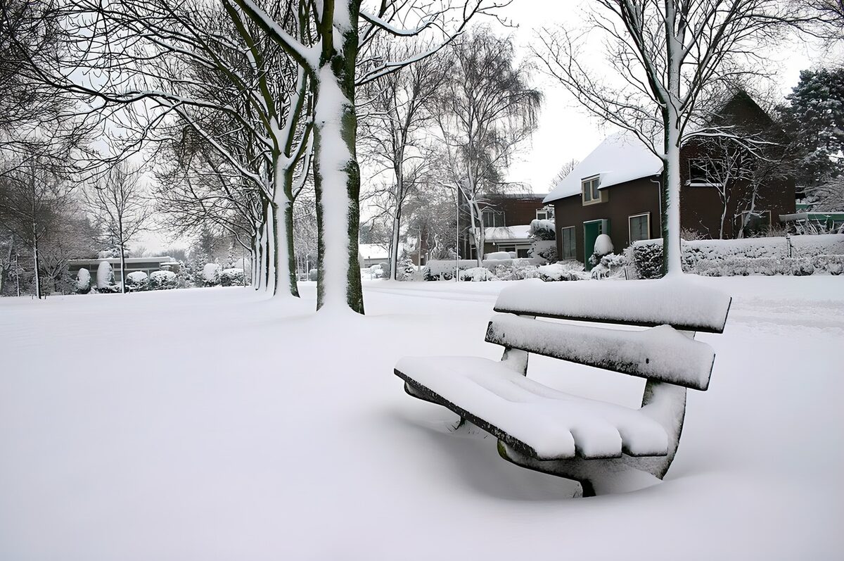 Holzbank und Häuser im tiefen Schnee