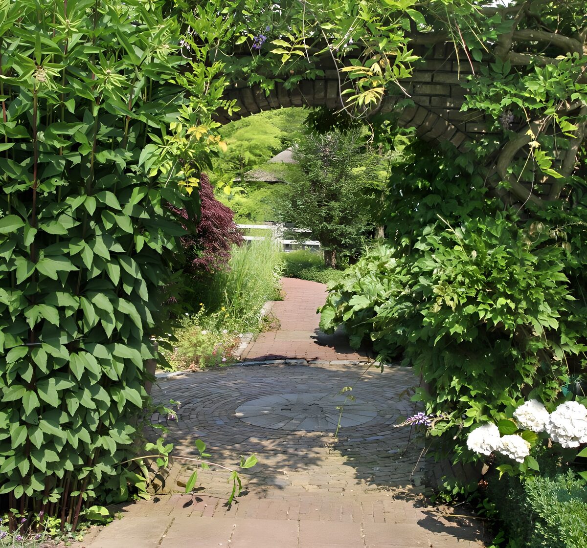 Gartenweg unter bewachsenem Ziegelbogen