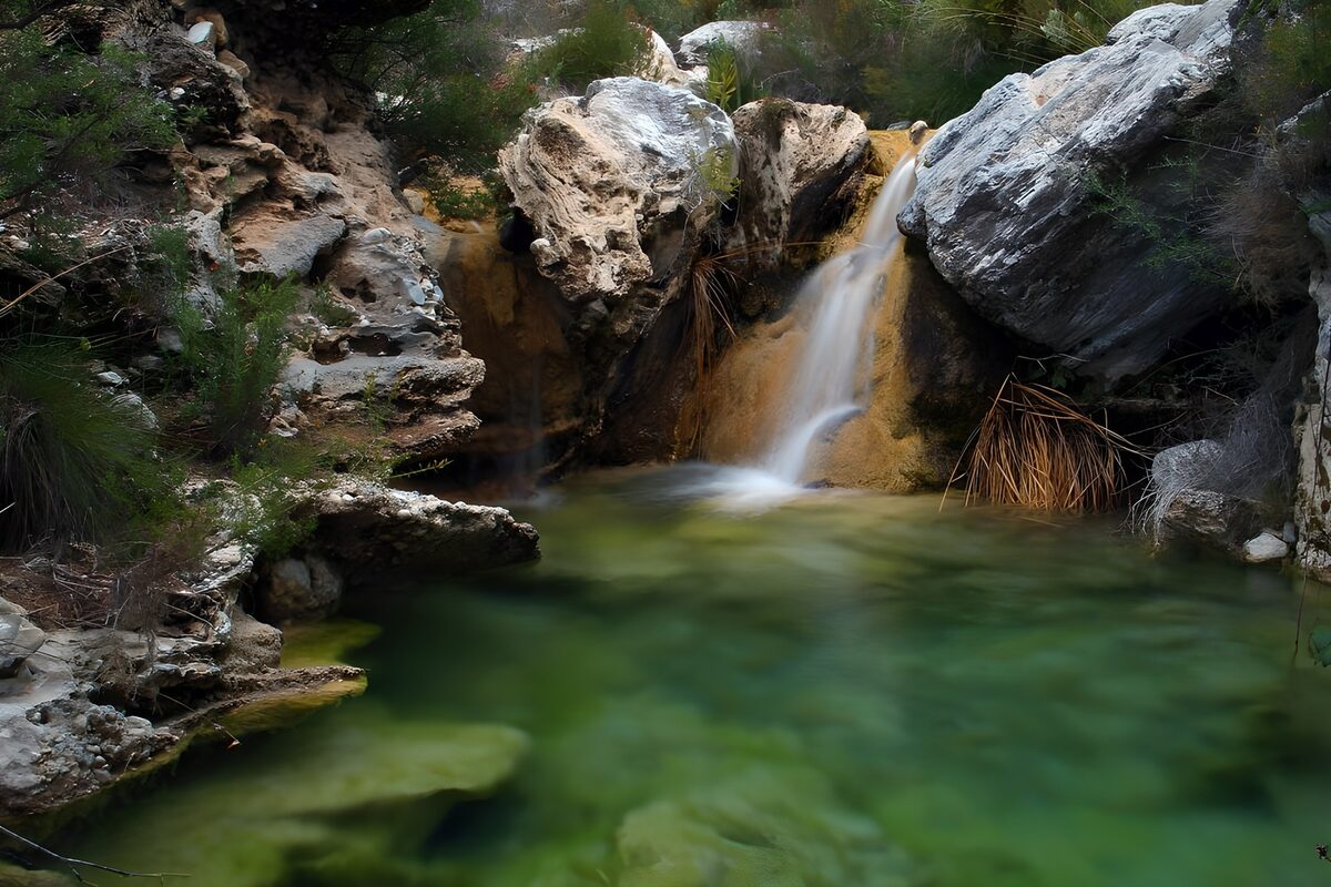 Kleiner Wasserfall im grünen Felsenbecken