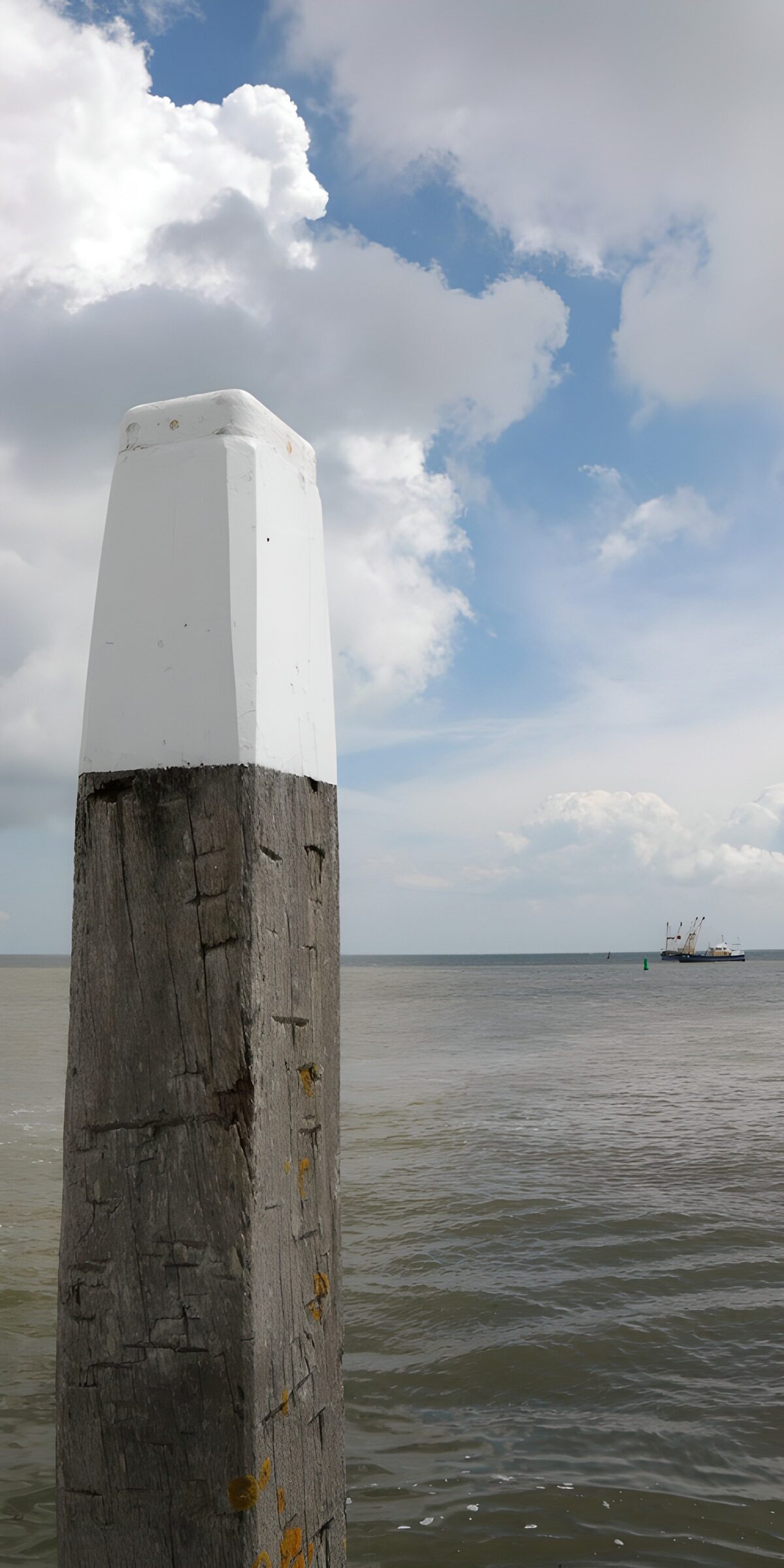 Anlegepfahl mit weißer Spitze am Meer