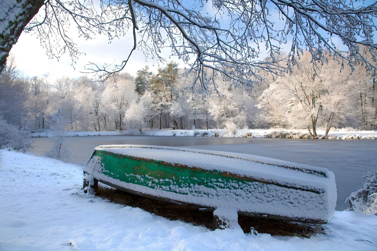 Grünes Ruderboot am verschneiten Teich