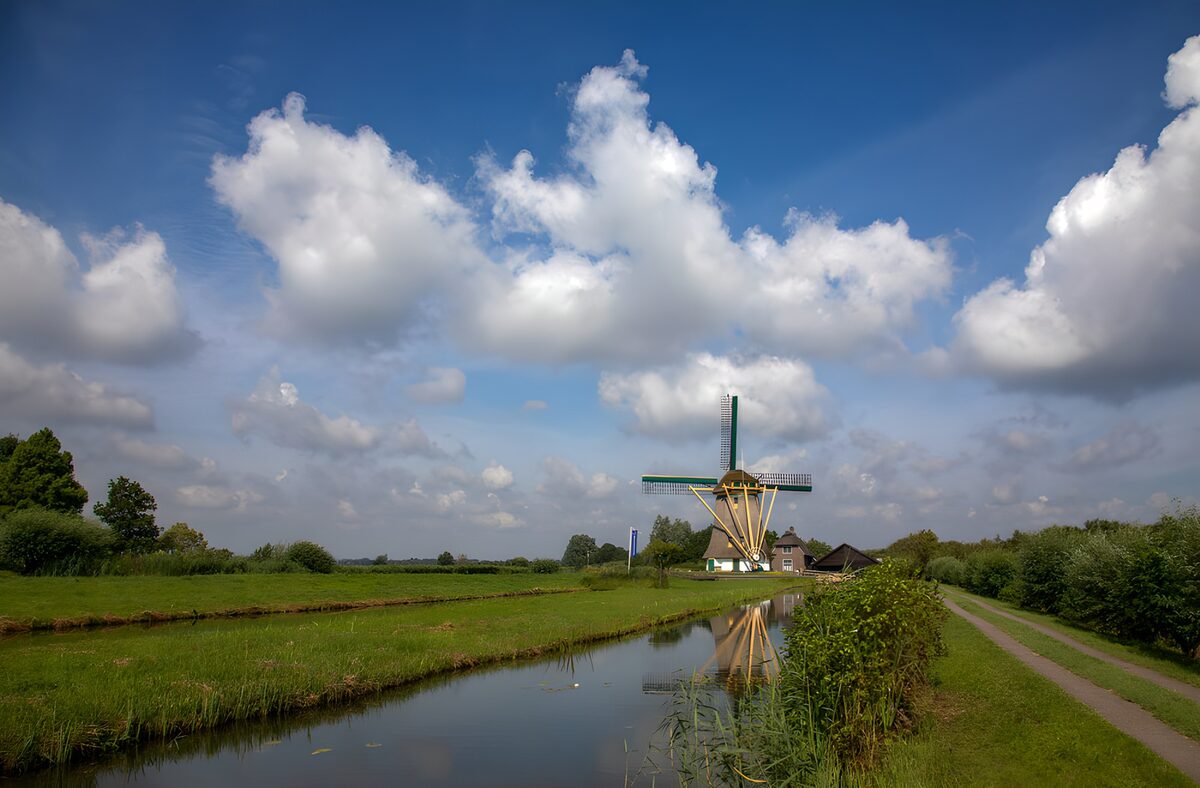 Windmühle zwischen Wiesen und Wolken