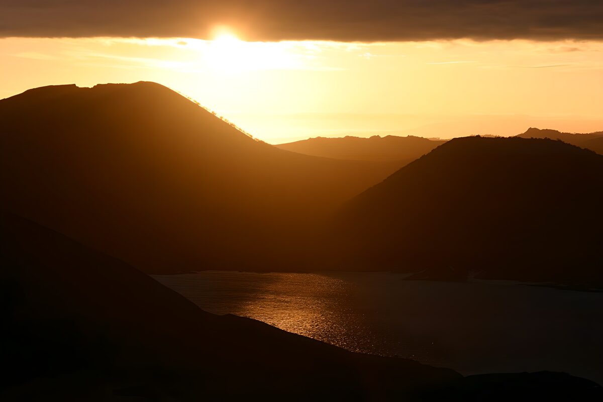 Bergsilhouetten über goldenem Wasser