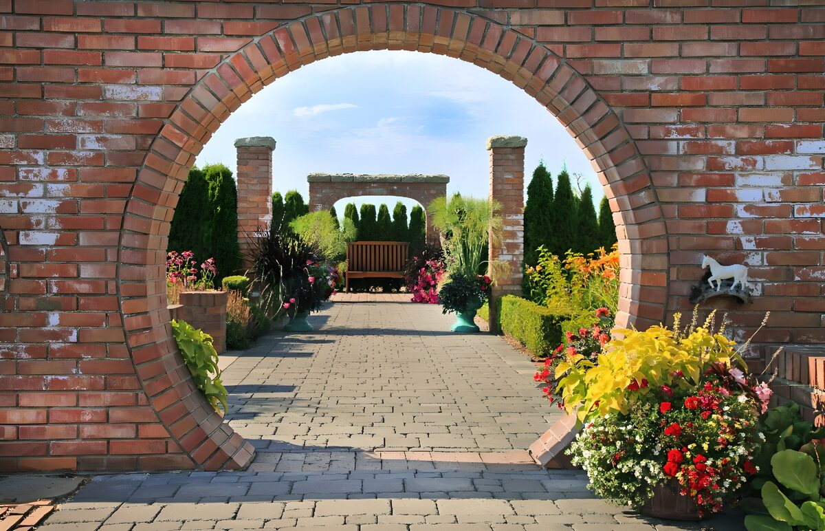 Sonniger Garten hinter rundem Ziegeltor