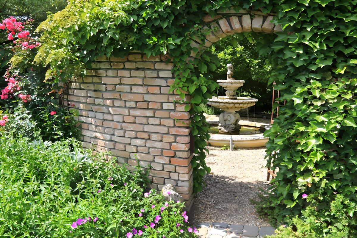 Gartenbrunnen hinter dem Efeubogen