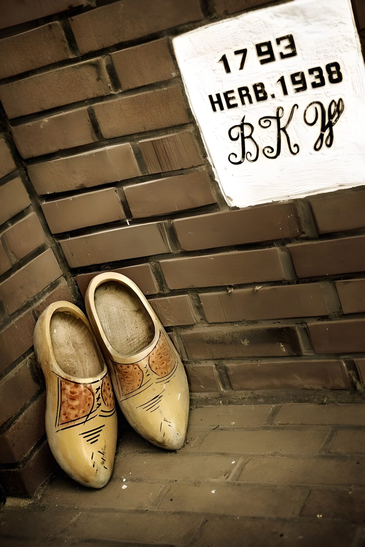Verzierte Holzschuhe an rauer Backsteinwand