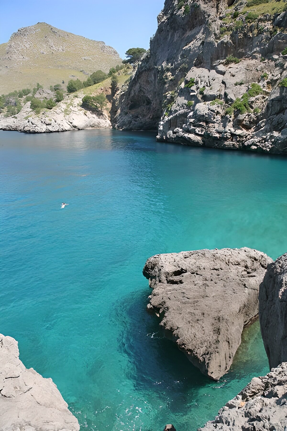 Sonnige Felsenbucht mit türkisblauem Wasser