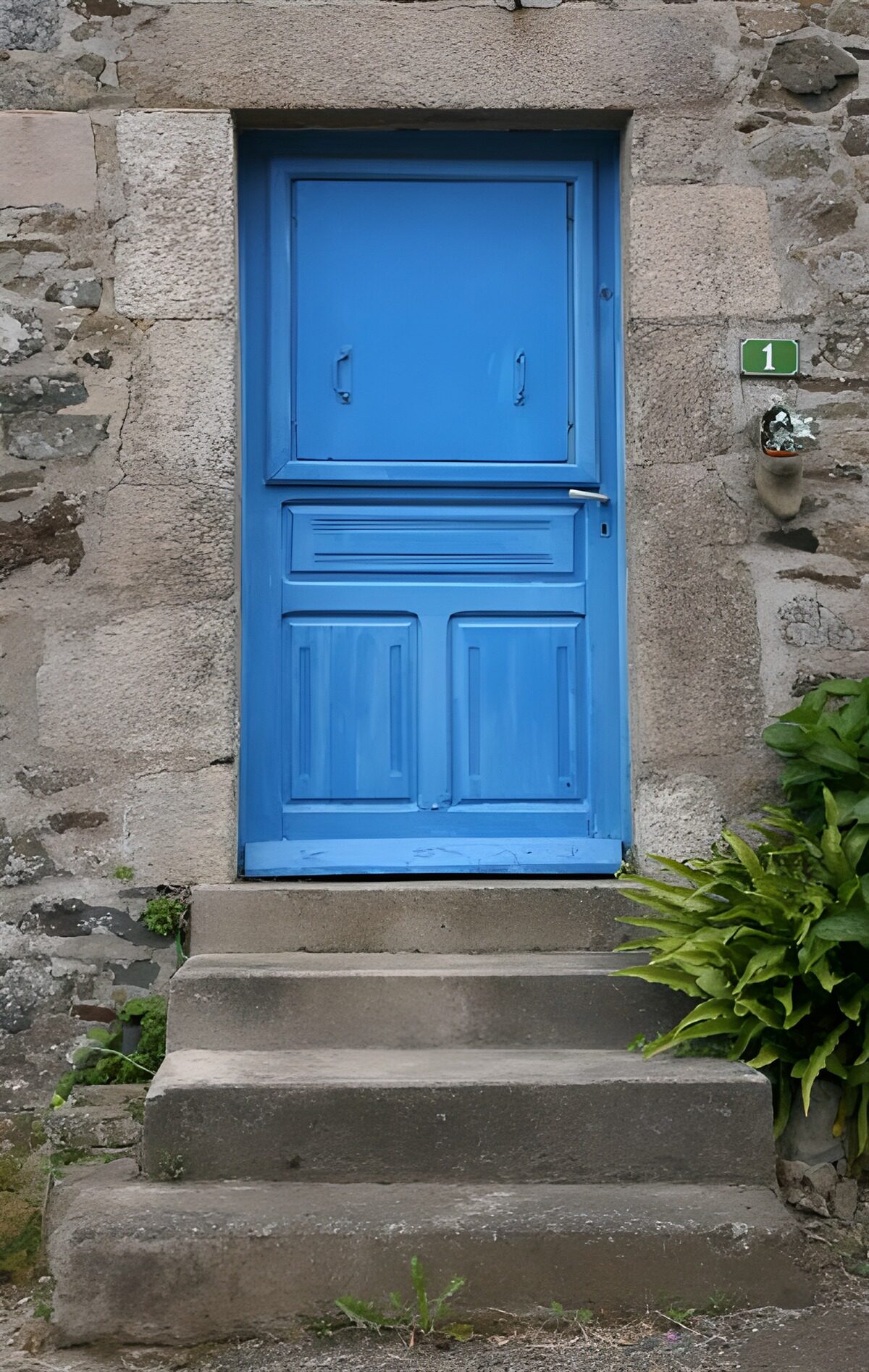 Blaue Holztür an verwitterter Steinmauer
