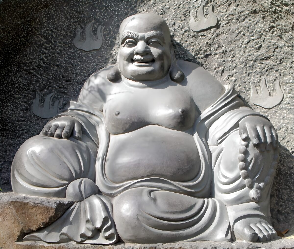 Lächelnder Buddha vor rauem Fels