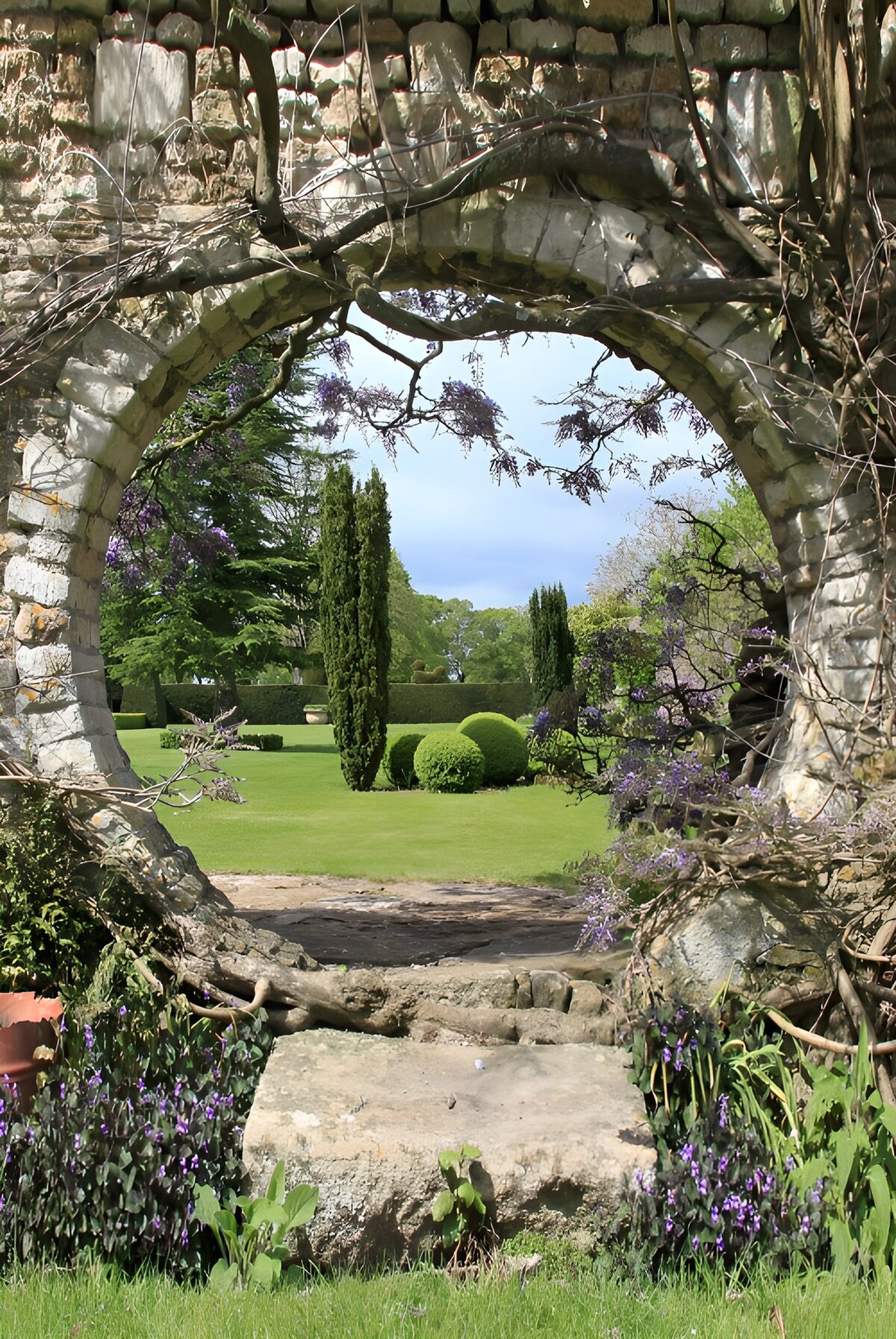Sonniger Garten hinter altem Steinbogen