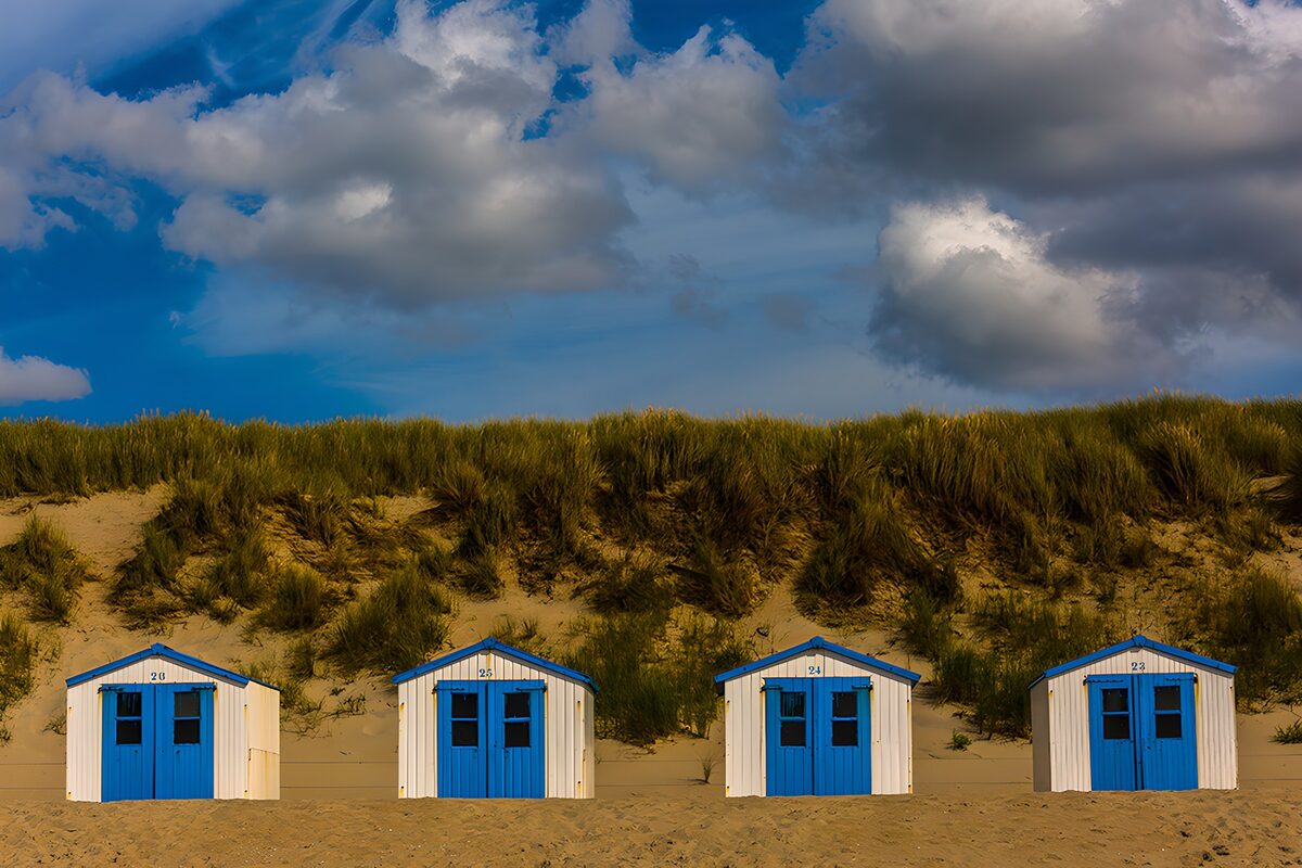 Strandhütten mit blauen Türen im Dünensand