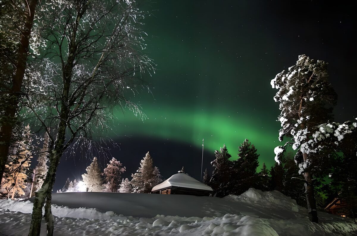 Hütte im Schnee unter grünem Nordlicht