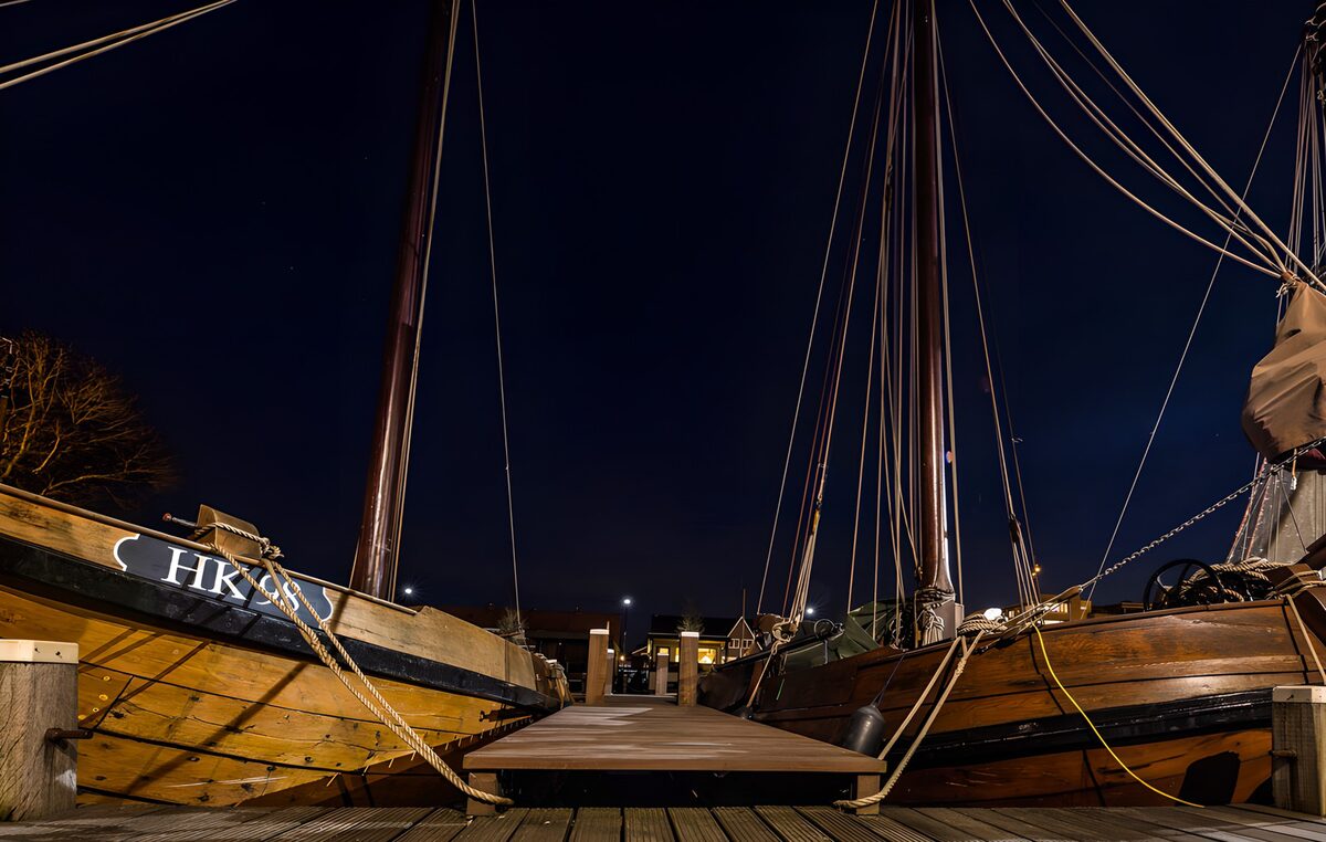 Zwei Holzsegler am Steg bei Nacht
