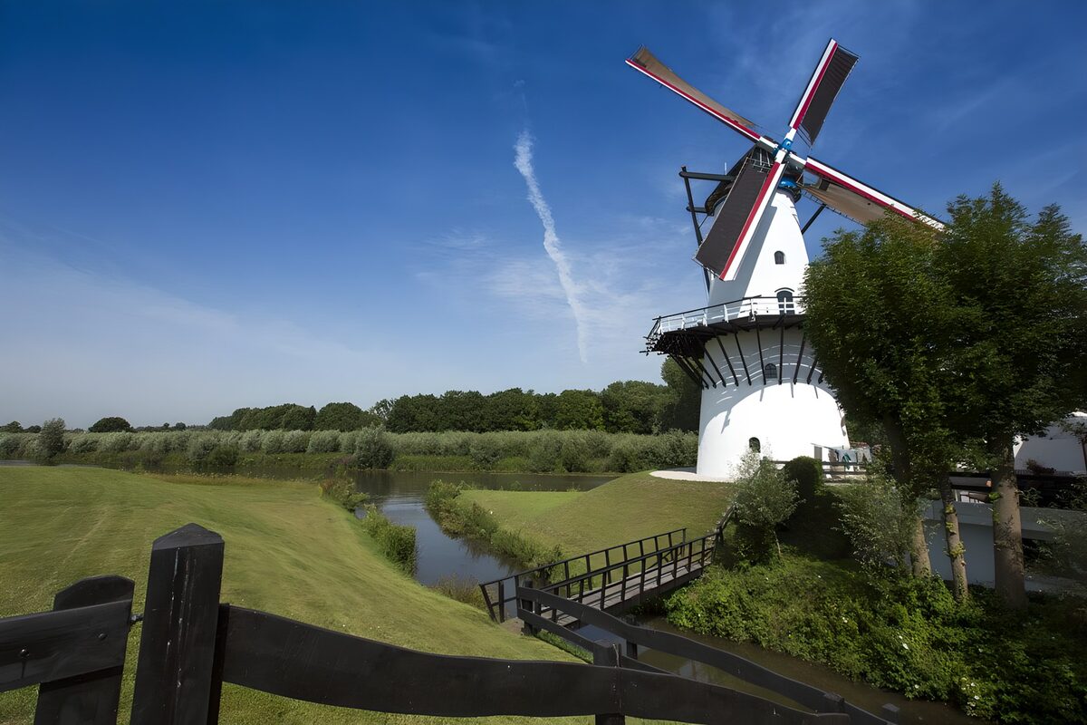 Weiße Windmühle am grünen Kanalufer
