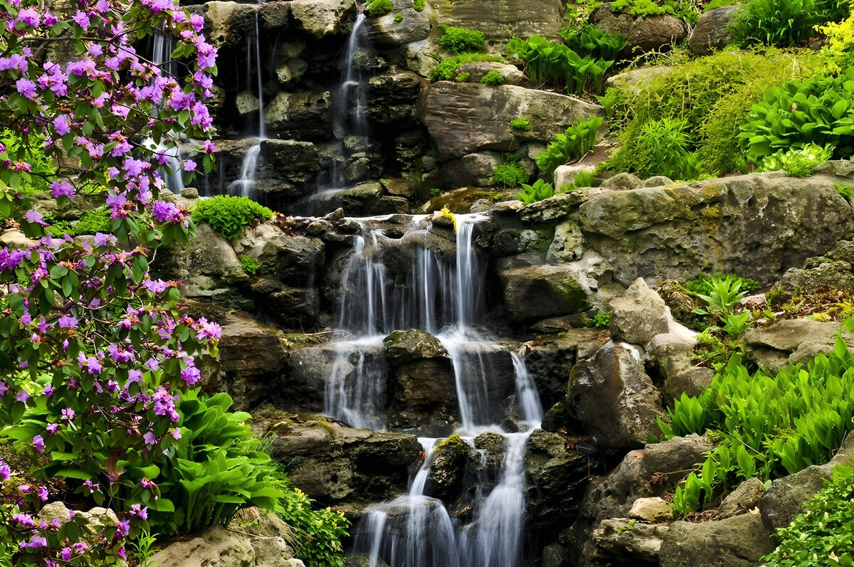 Gartenwasserfall mit pinken Blüten