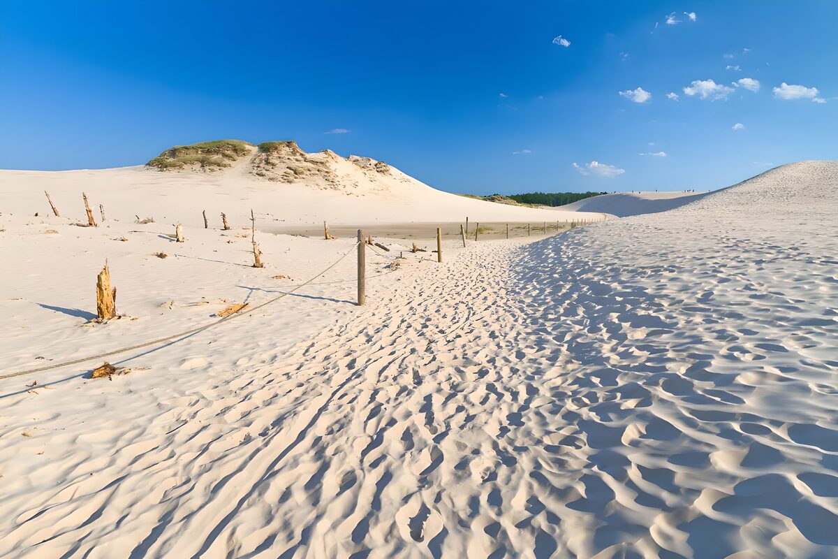 Sandweg durch Dünen unter blauem Himmel