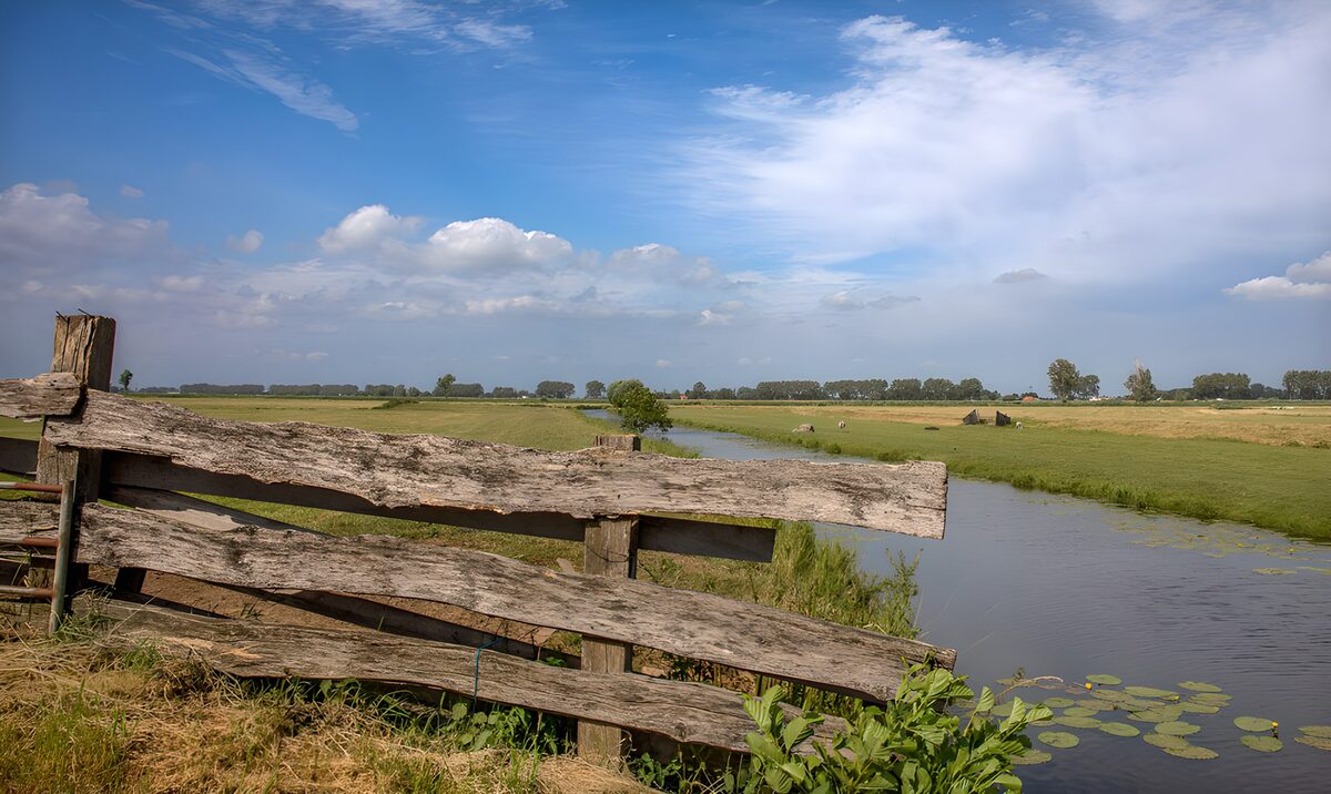 Holzzaun am Wasserlauf im Weideland