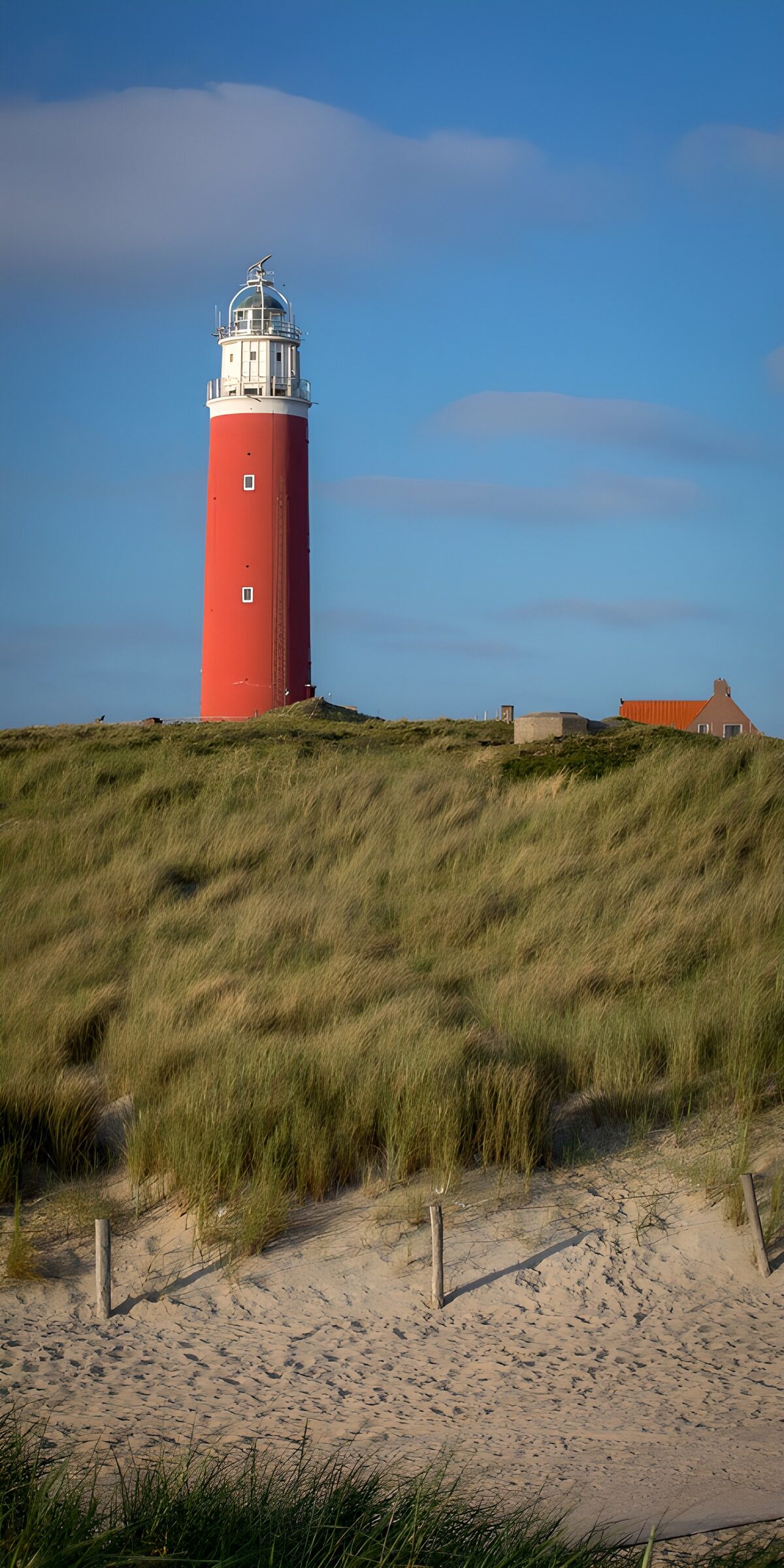 Roter Leuchtturm über stillen Dünen