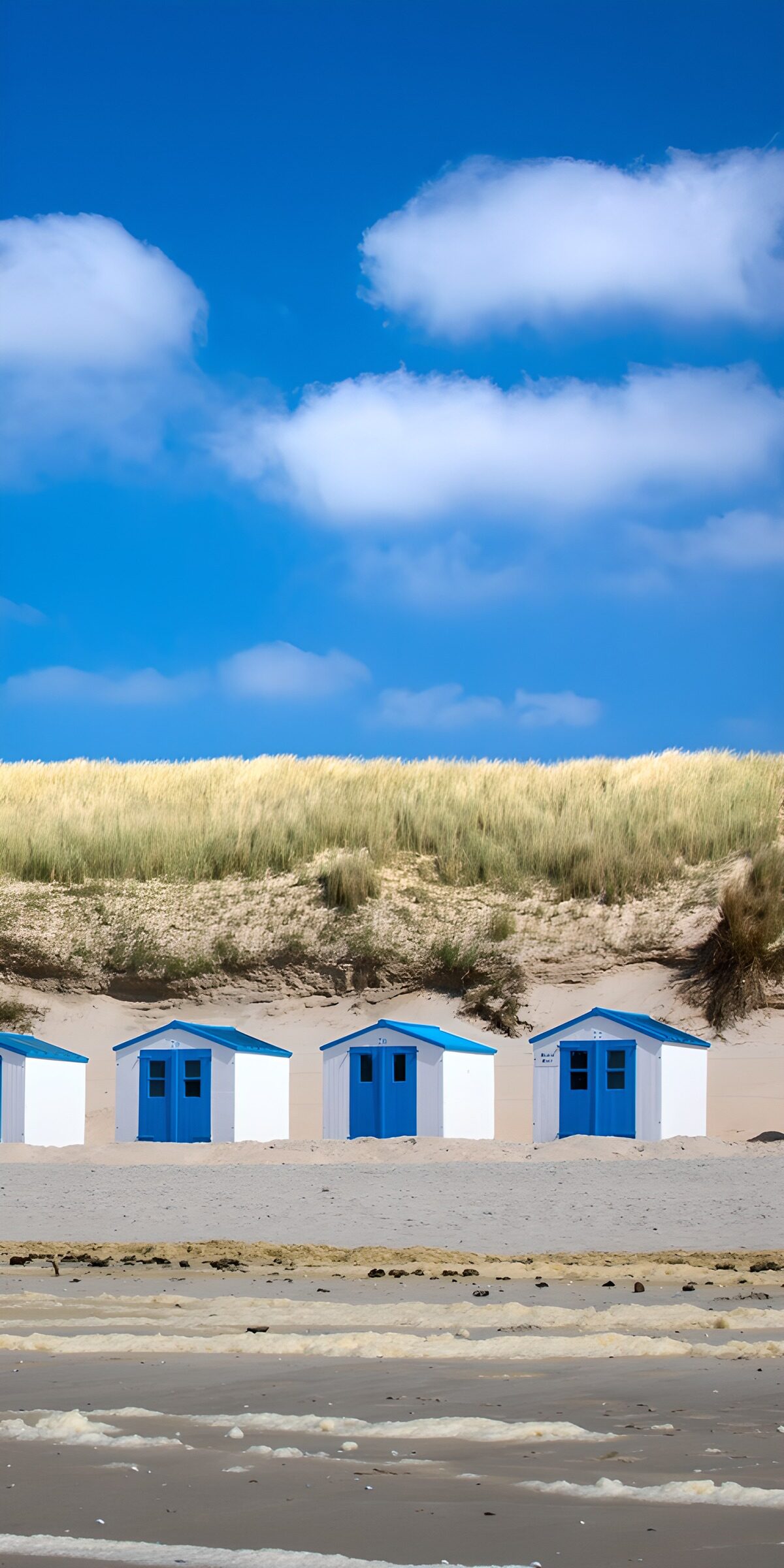 Blau-weiße Strandhütten vor den Dünen