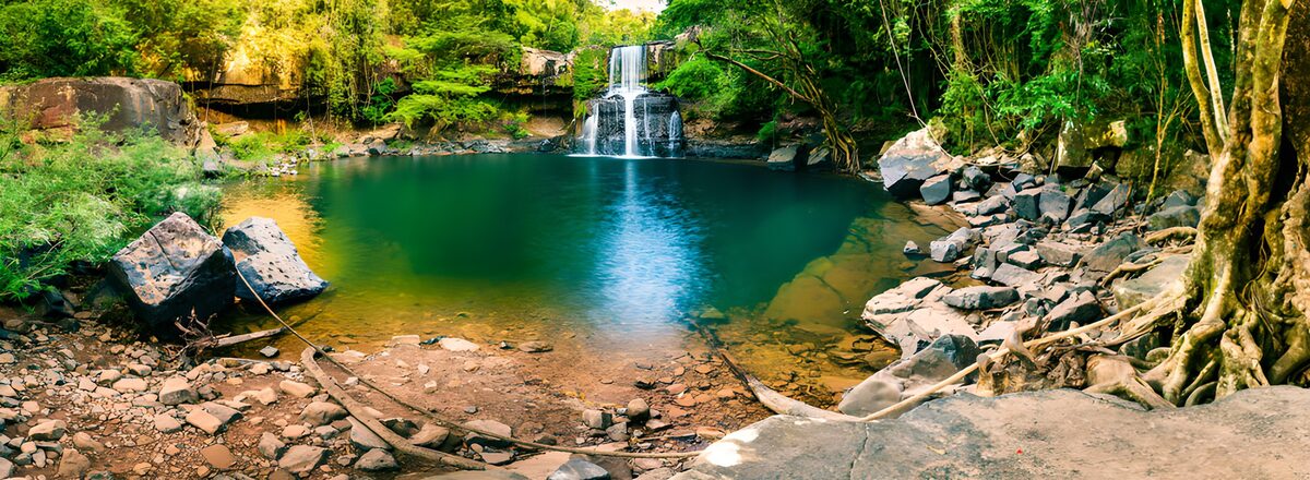 Kleiner Wasserfall am blaugrünen Waldbecken