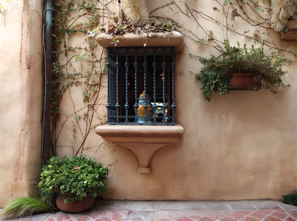 Gitterfenster mit Grün an warmer Fassade