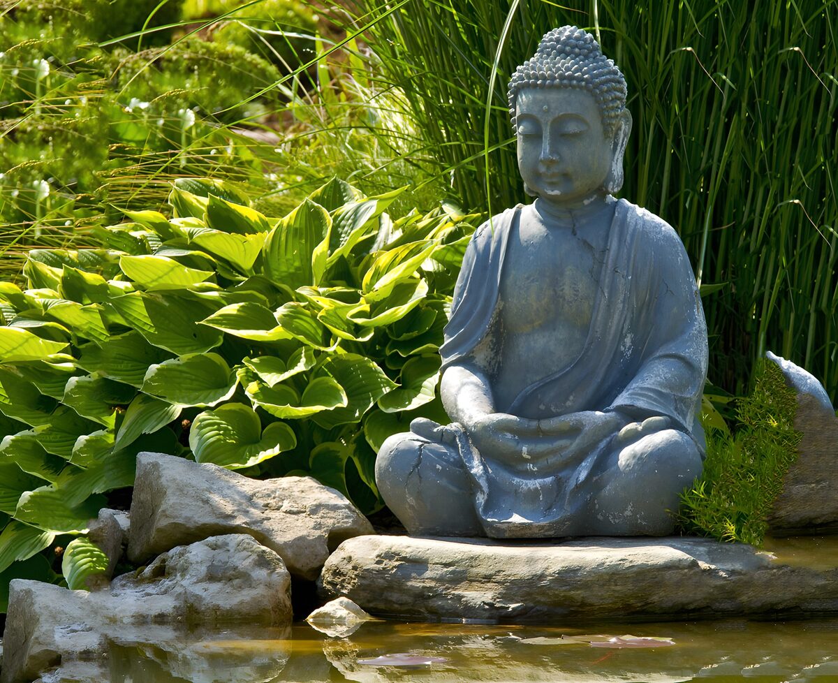 Buddha am Teich zwischen Steinen und Grün