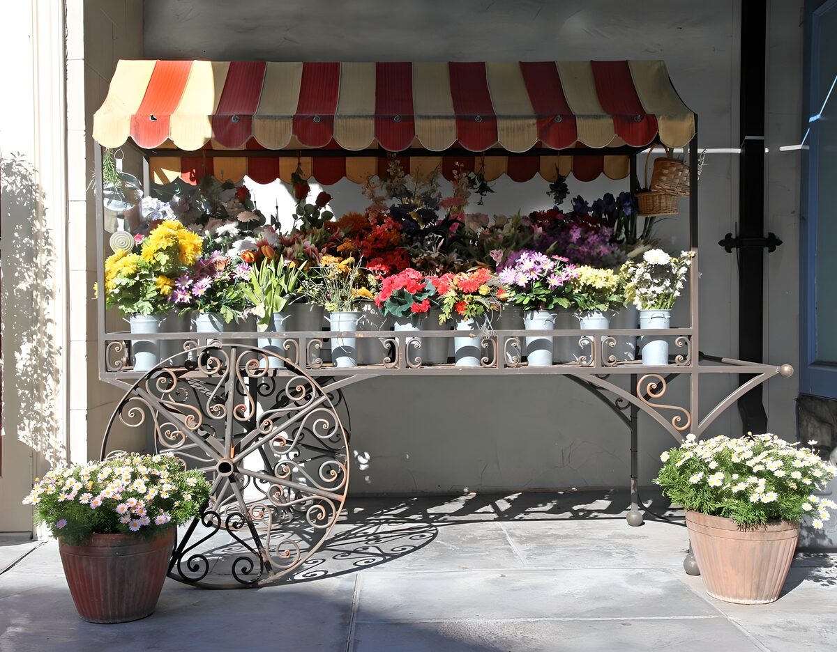 Blumenwagen unter rot-cremefarbener Markise