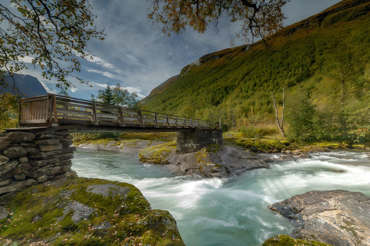 Holzbrücke über schäumendem Bergfluss