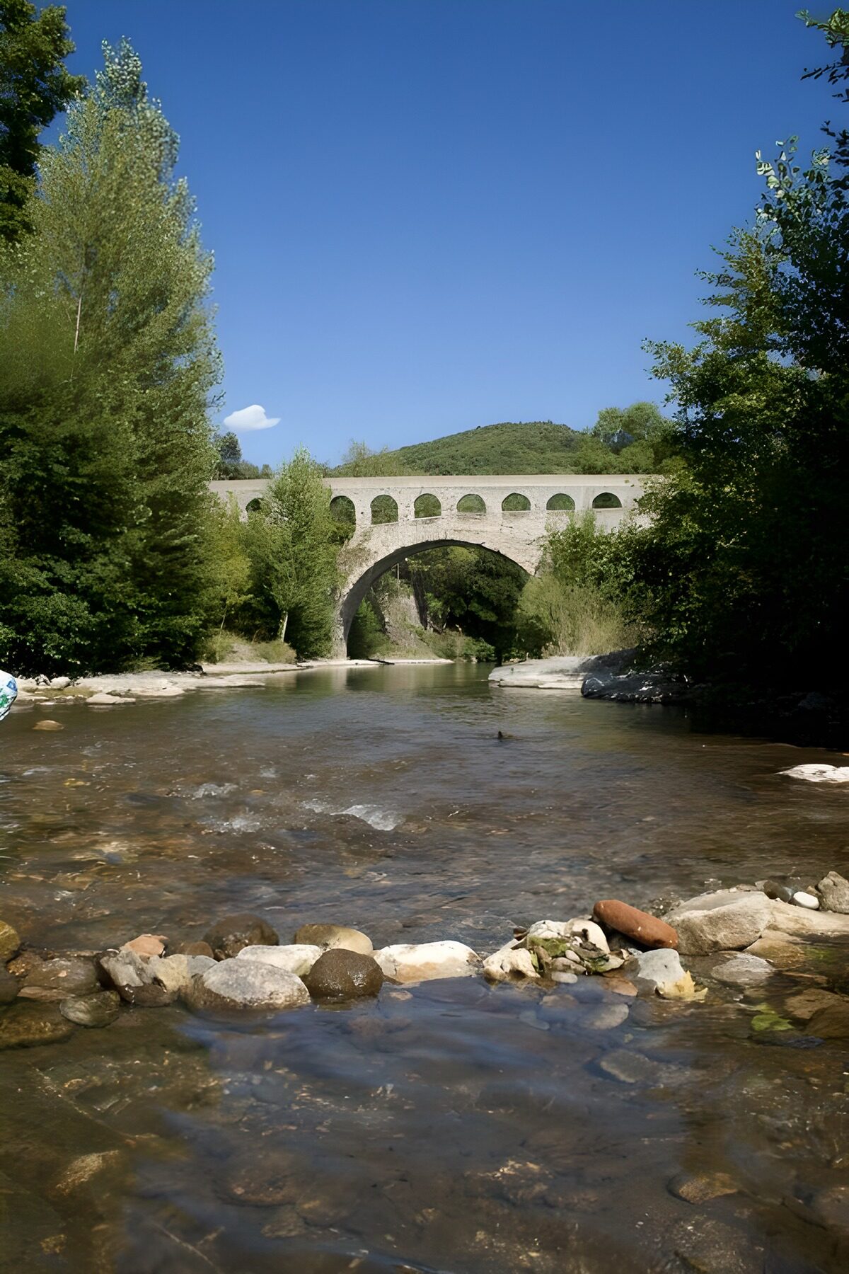Steinbrücke über dem Fluss im Sommergrün