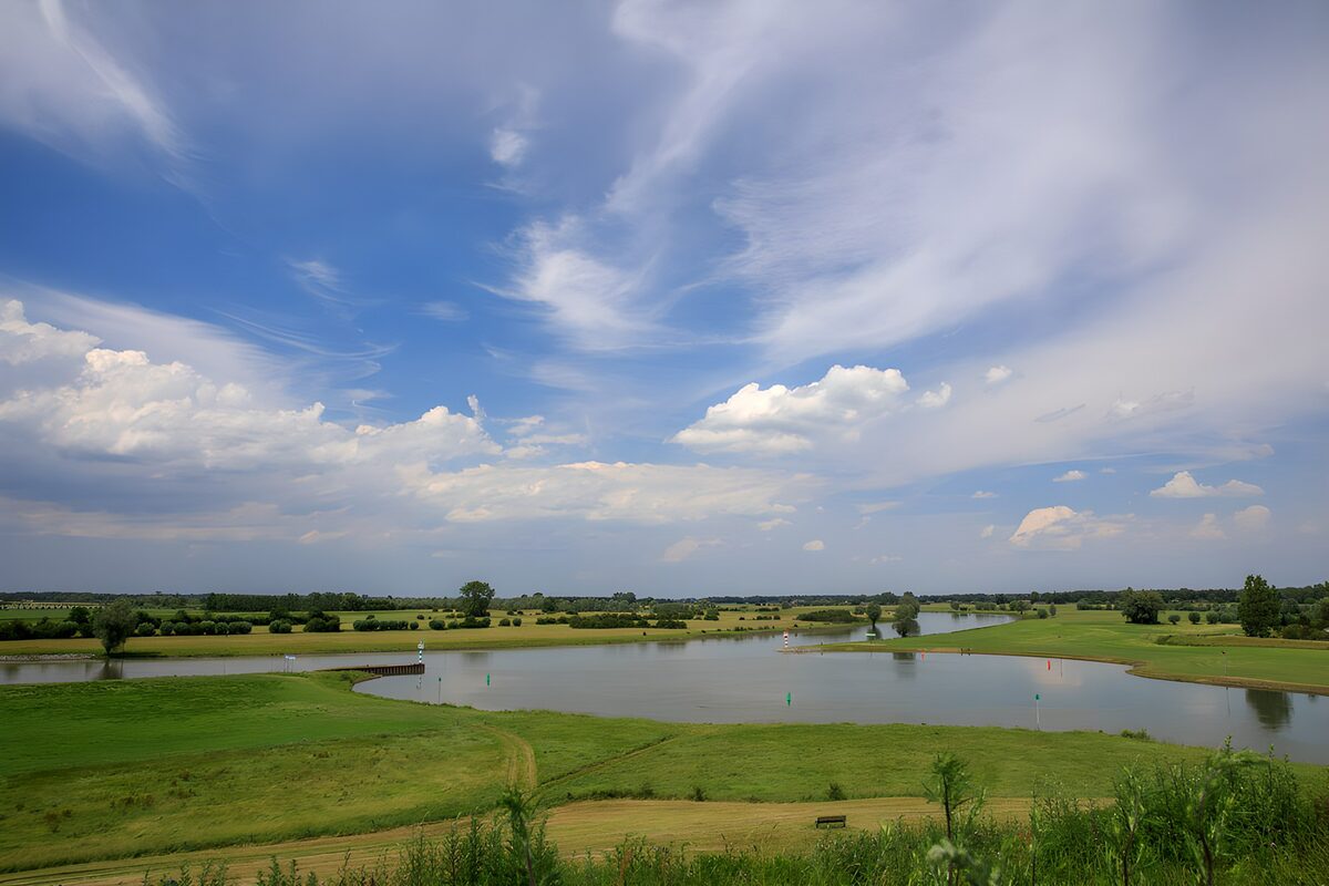 Teich mit Wiesen und weitem Wolkenhimmel