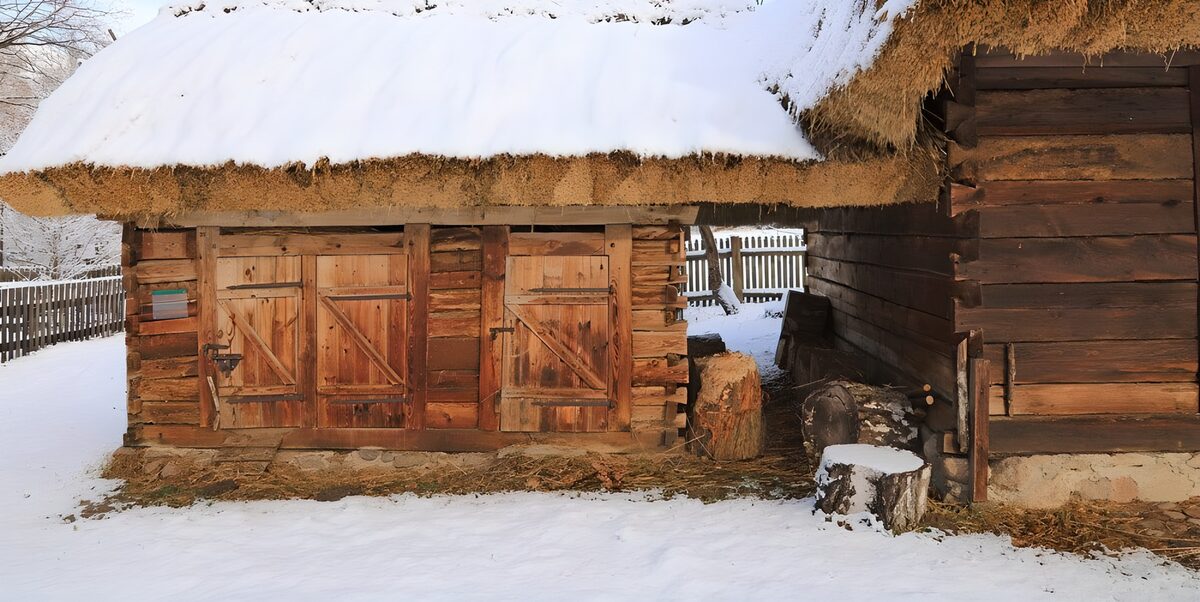 Holzschuppen mit schneebedeckten Strohdächern
