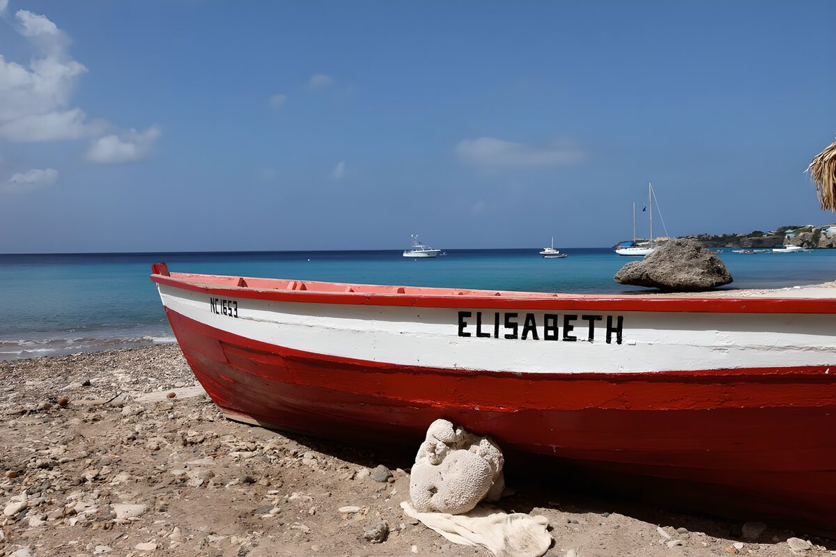 Rotes Holzboot am sonnigen Kiesstrand