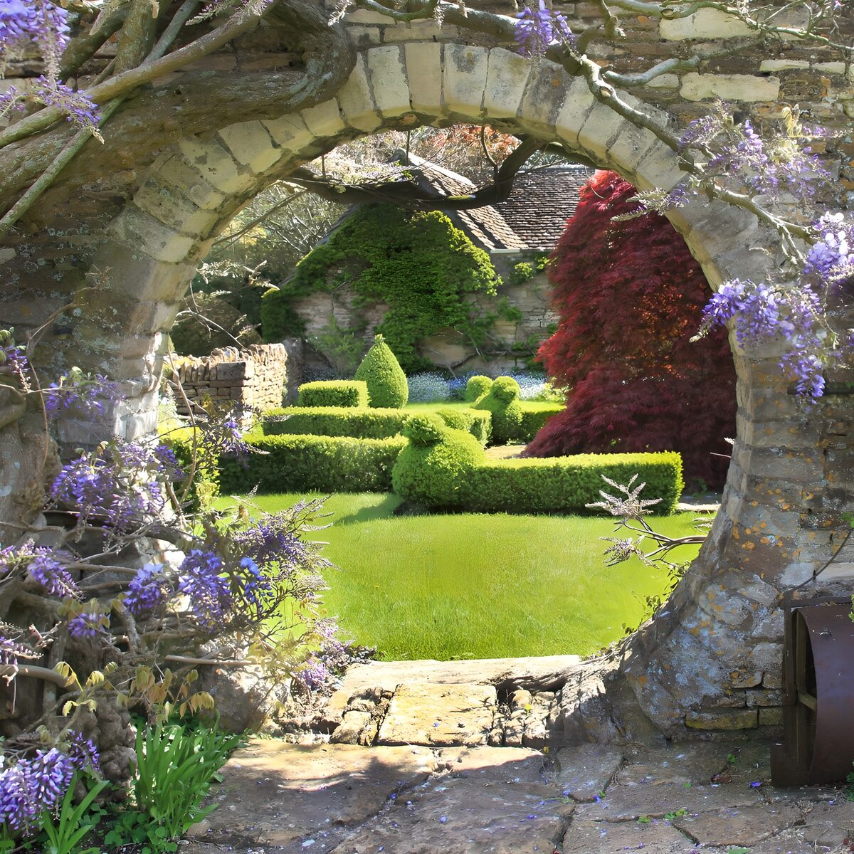 Steinbogen mit Blauregen und Gartenblick