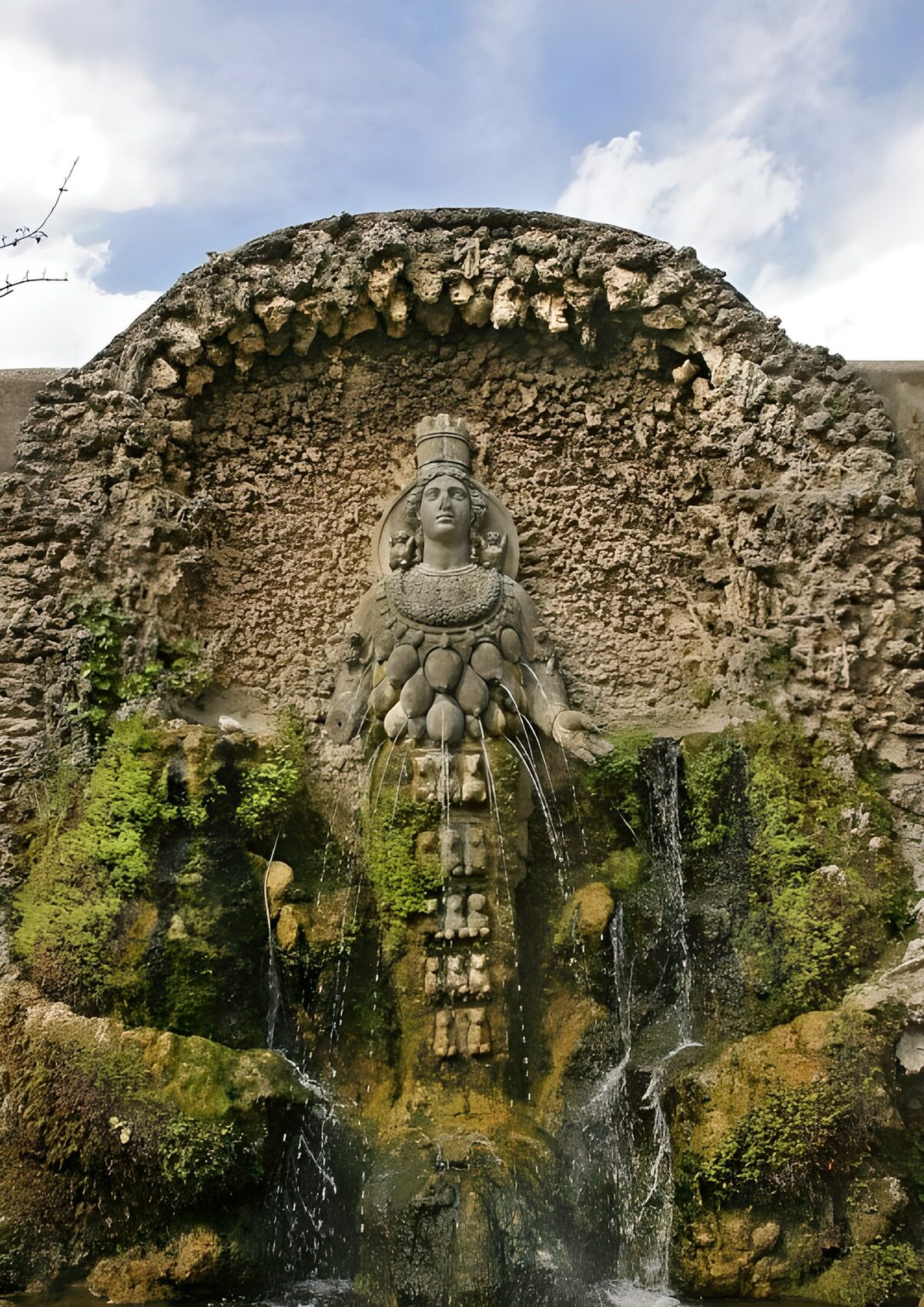 Steinbrunnen mit Frauenfigur im grünen Moos