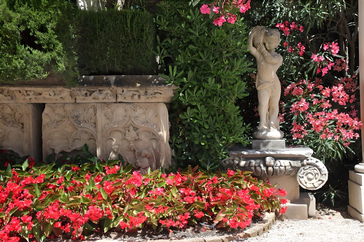 Kinderstatue zwischen roten und rosa Blüten
