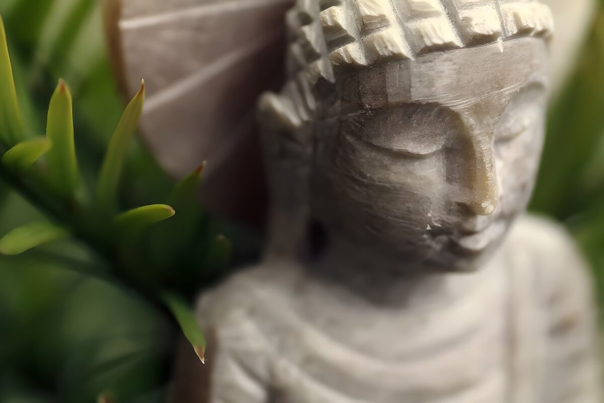 Graue Buddha-Statue zwischen grünen Blättern