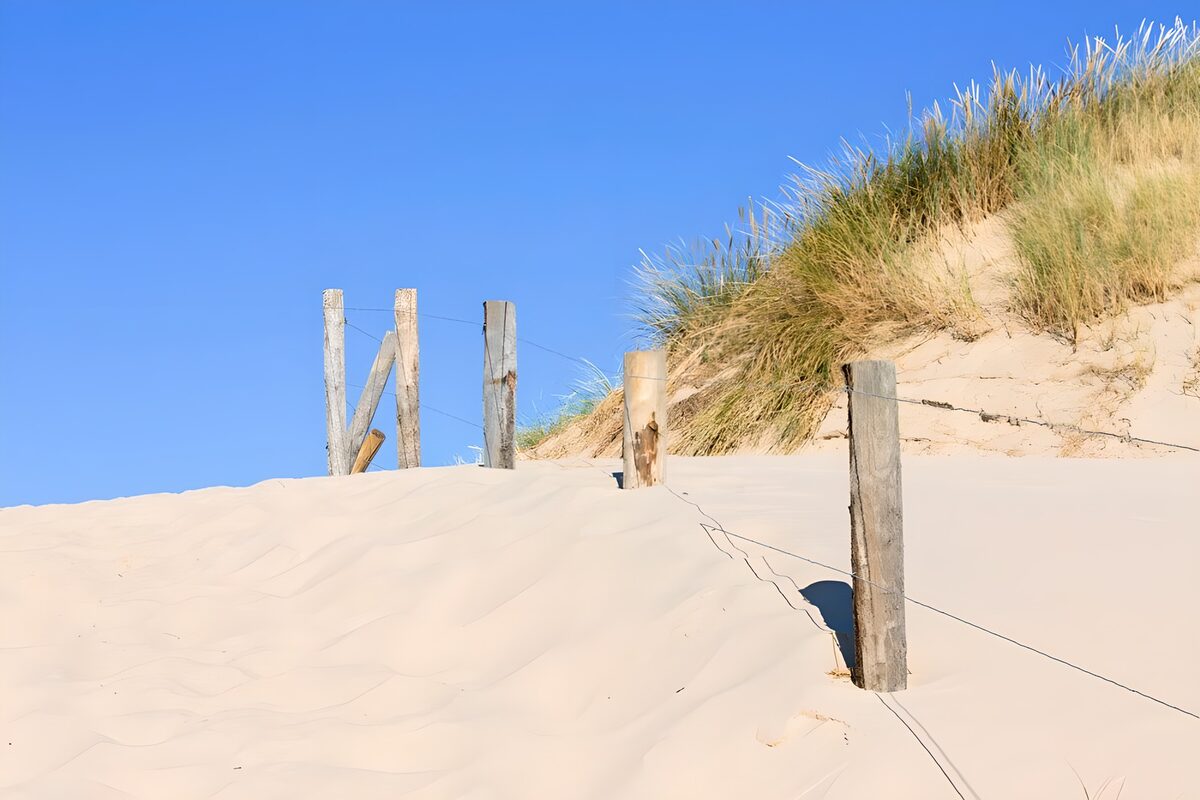 Ein Zaun zwischen Sand und Himmel