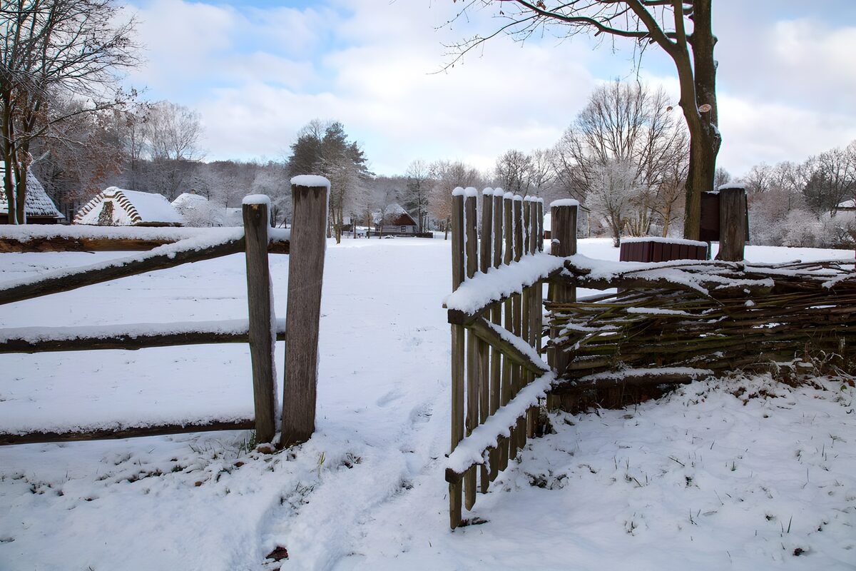 Offenes Holztor in stiller Schneelandschaft