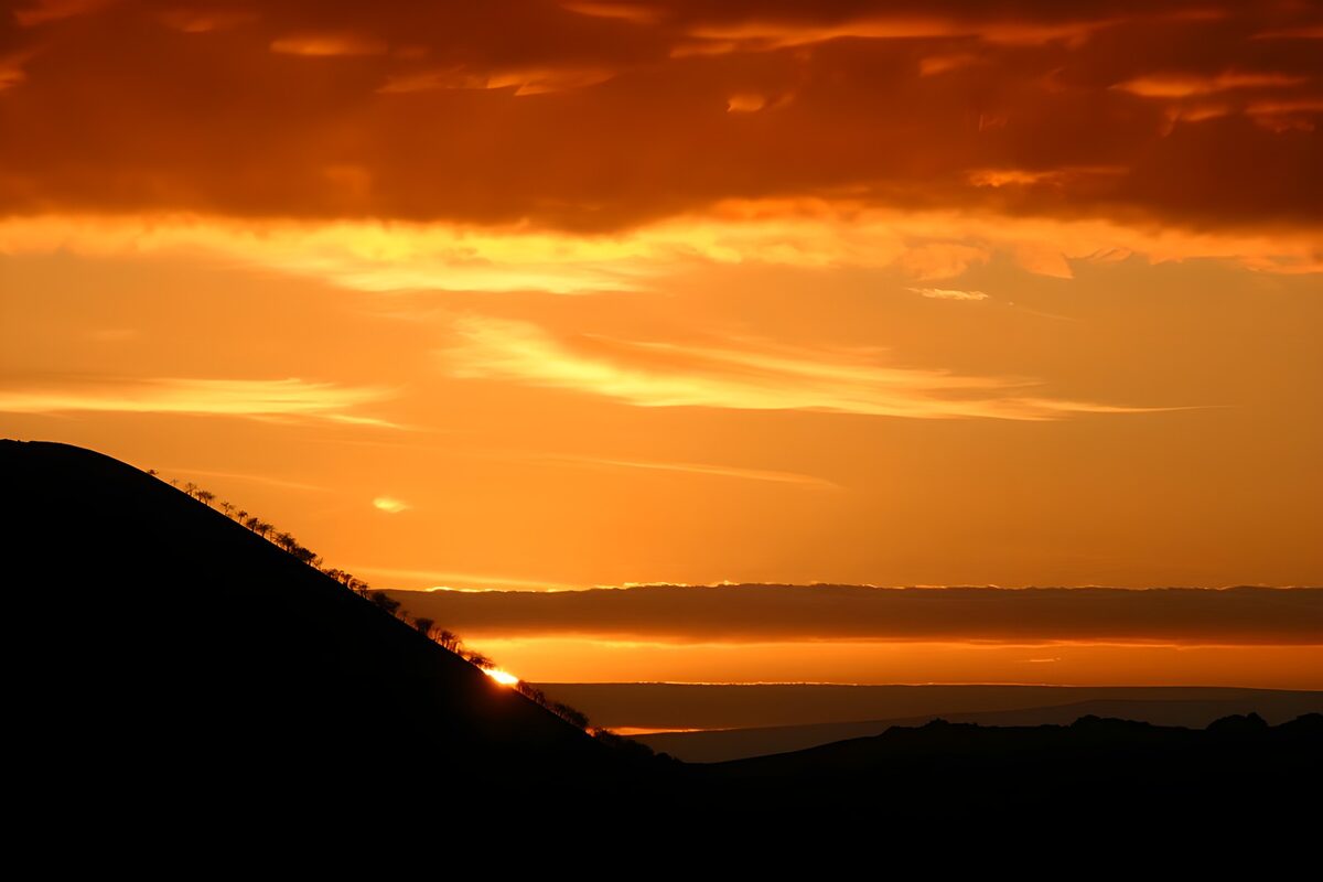 Sonnenuntergang hinter dunklen Hügeln