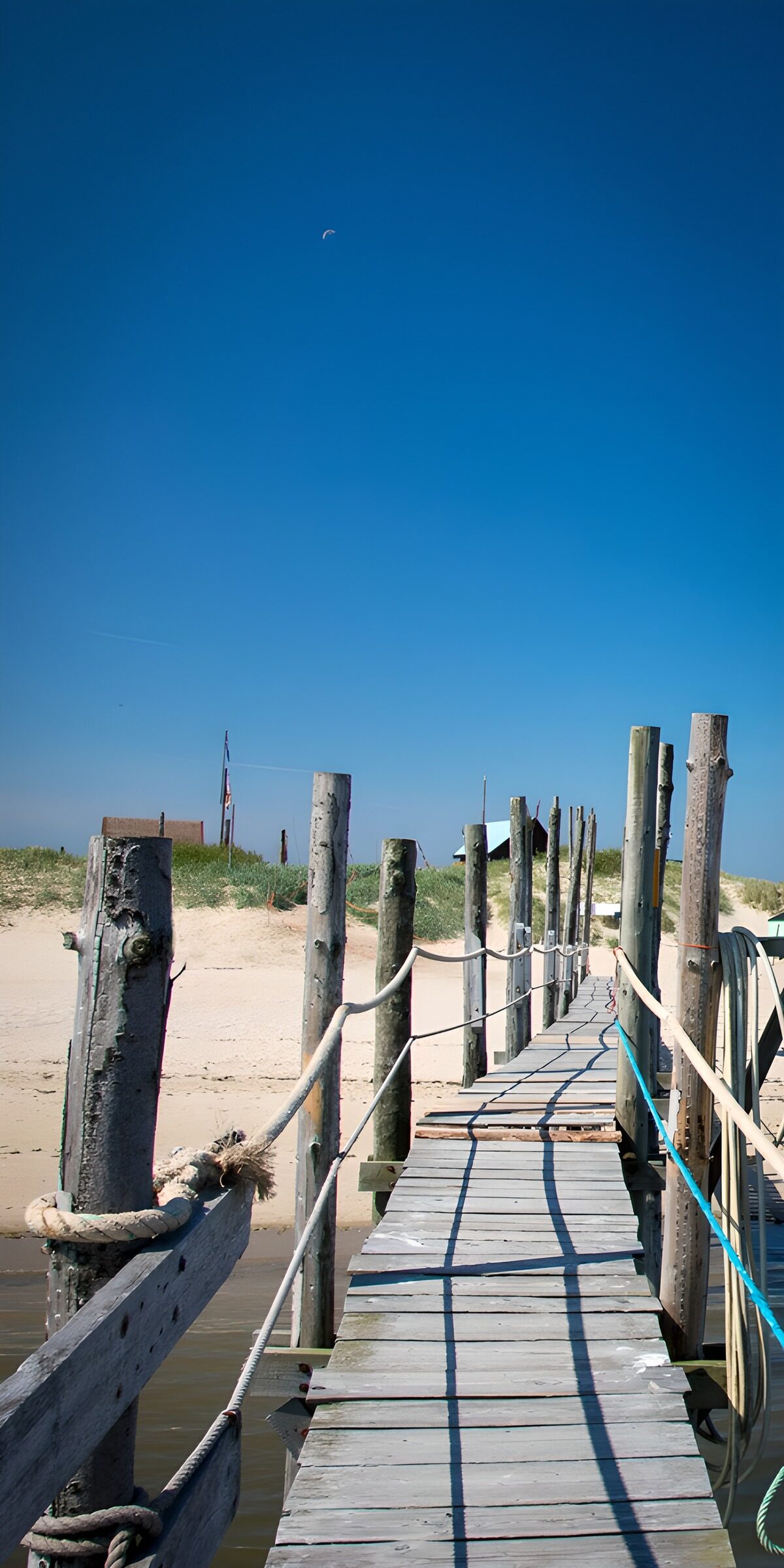Sonniger Holzsteg am Sandstrand
