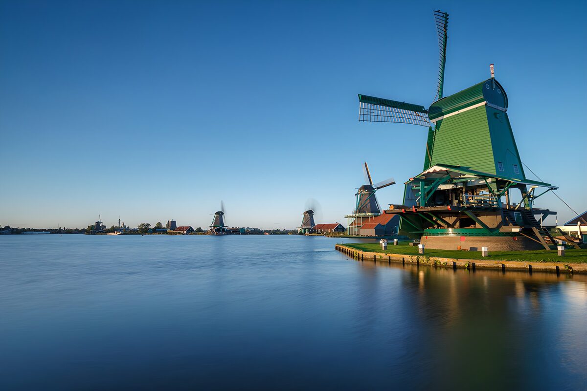 Grüne Windmühle am sonnigen Kanalufer