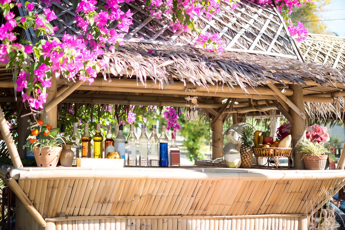 Bambusbar mit pinken Blüten und Strohdach