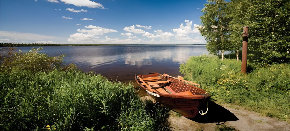 Holzruderboot am sonnigen Seeufer