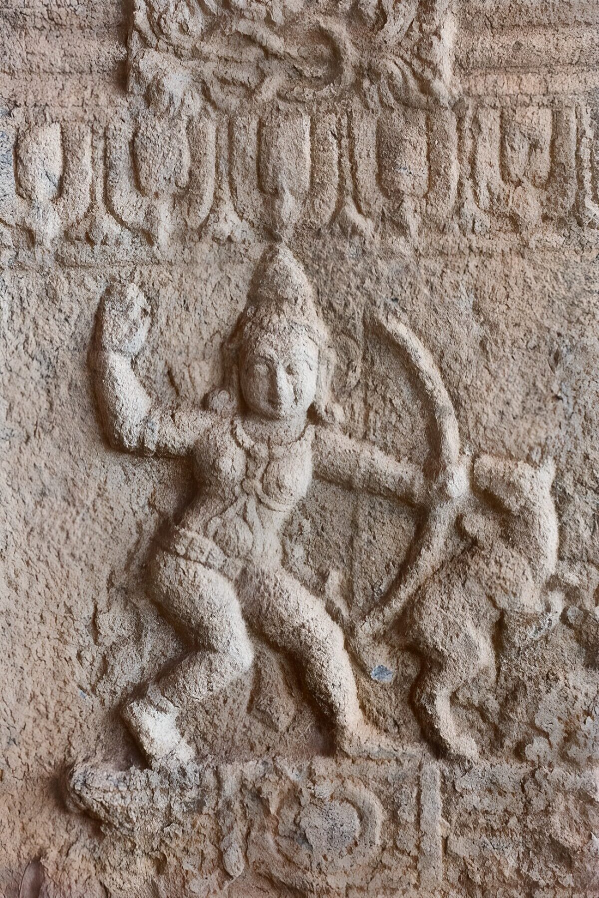Verwitterte Bogenfigur im Steinrelief