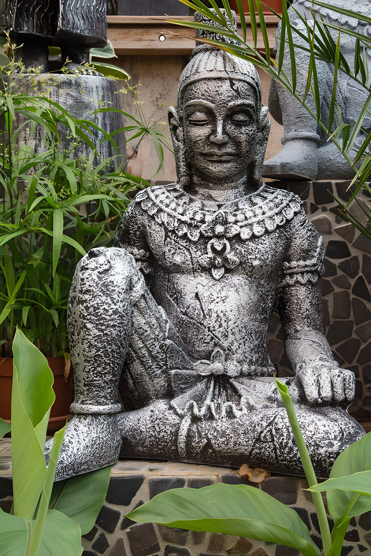Graue Steinfigur im dichten Grün