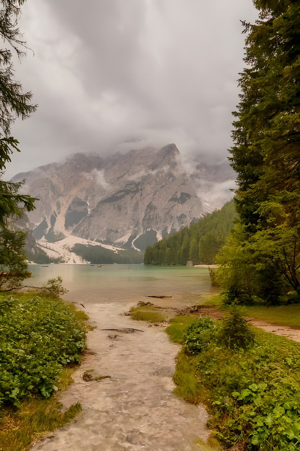 Stiller Bergsee unter nebligen Felswänden