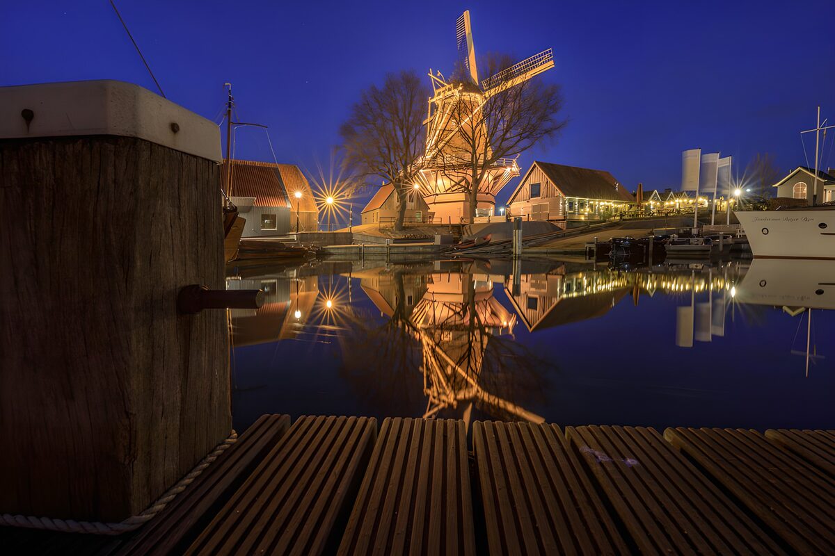 Beleuchtete Windmühle am stillen Hafen